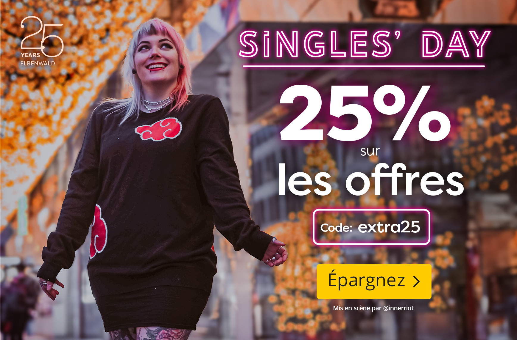 Personne portant un pull noir et rouge Akatsuki de Naruto sourit en marchant dans une rue illuminée. Texte : “Singles’ Day, 25 % sur les offres, Code : extra25, Épargnez”.