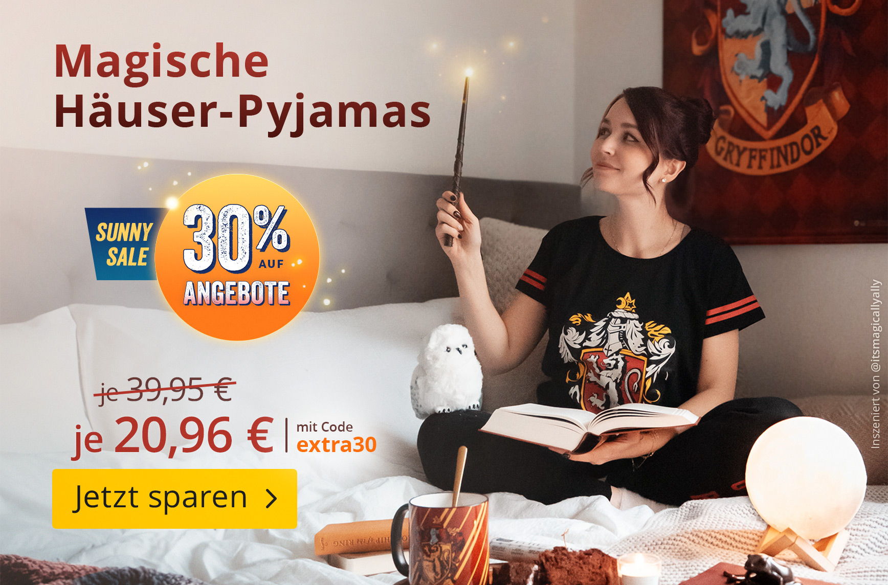 Eine Person sitzt gemütlich im Bett, trägt einen Harry Potter Häuser-Pyjama und hält einen leuchtenden Zauberstab in der Hand. Im Bild stehen der Text „Magische Häuser-Pyjamas“, der Hinweis „30 % auf Angebote“, der reduzierte Preis von je 39,95 € auf je 2