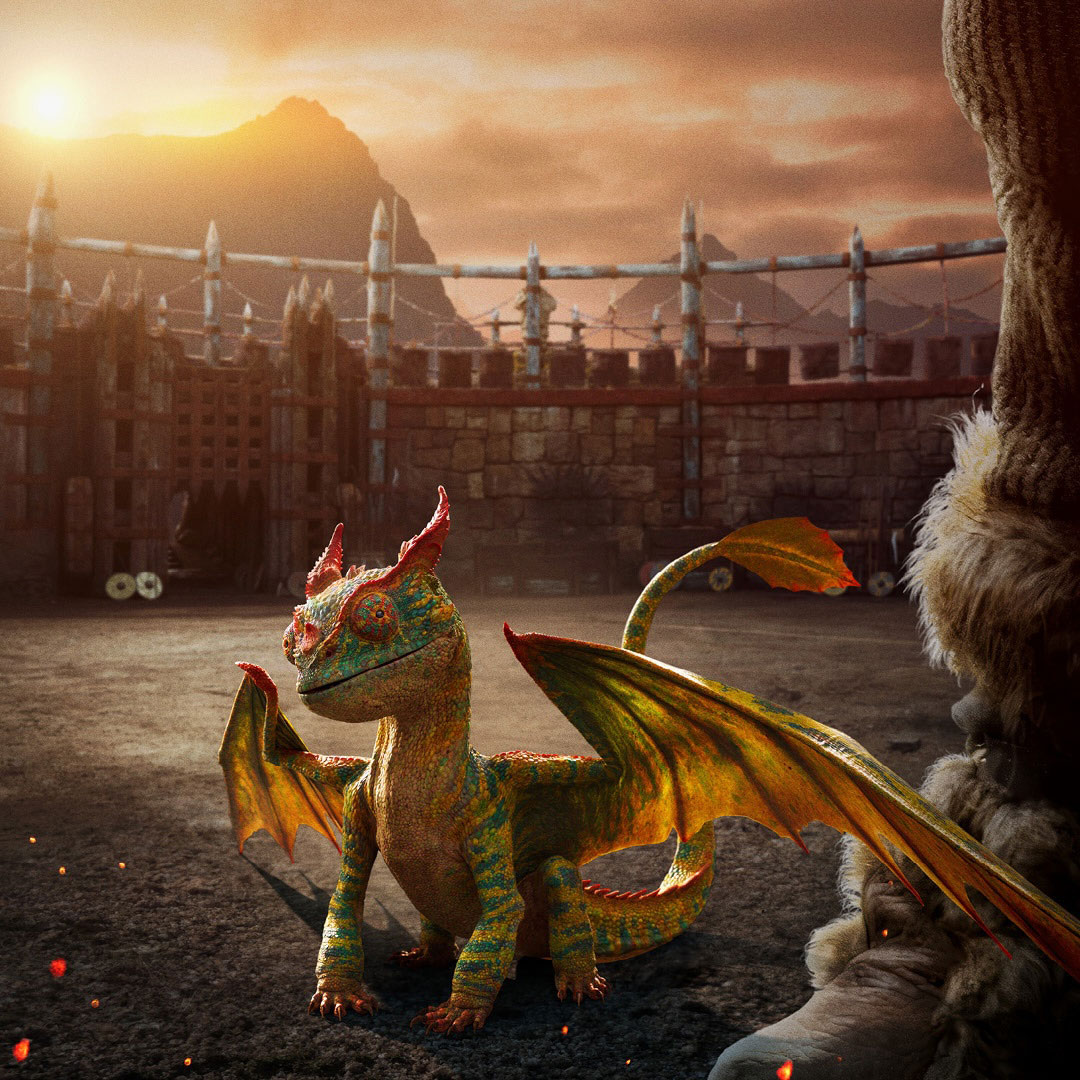 A small, colorful dragon with large eyes stands on an arena floor at sunset. A wooden arena structure can be seen in the background.