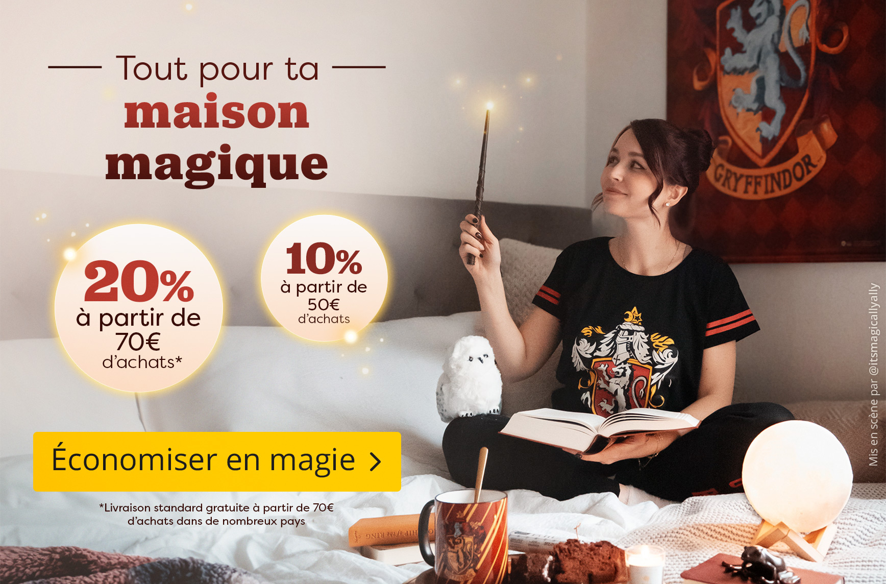 Femme portant un pyjama Gryffondor assise confortablement sur un lit, tenant une baguette lumineuse et lisant un livre. Une figurine de hibou, une tasse Gryffondor et une décoration magique sont posées sur le lit. Texte : « Tout pour ta maison magique, 20
