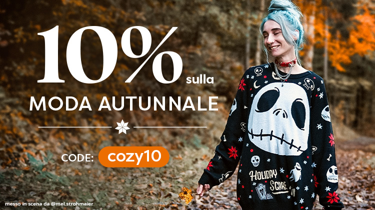 Persona con capelli azzurri e collare rosso indossa un maglione nero con Jack Skellington di Nightmare Before Christmas in un bosco autunnale. Testo: “10% di sconto sulla moda autunnale, Codice: cozy10.