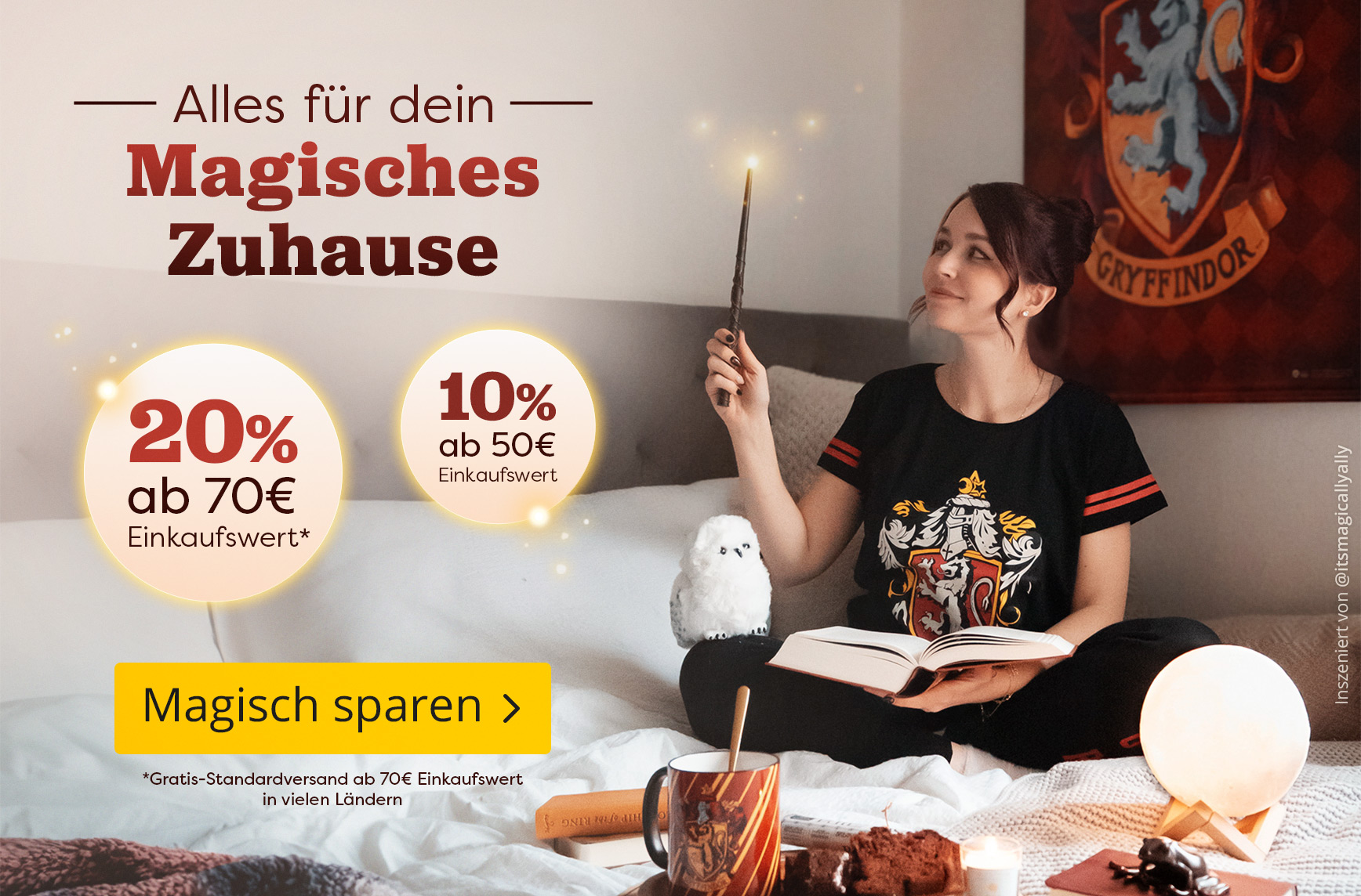 Frau im Gryffindor-Pyjama sitzt gemütlich auf dem Bett, hält einen leuchtenden Zauberstab und liest ein Buch. Auf dem Bett stehen eine Eulenfigur, eine Gryffindor-Tasse und magische Deko. Text: „Alles für dein magisches Zuhause, 20 % ab 70 € Einkaufswert,