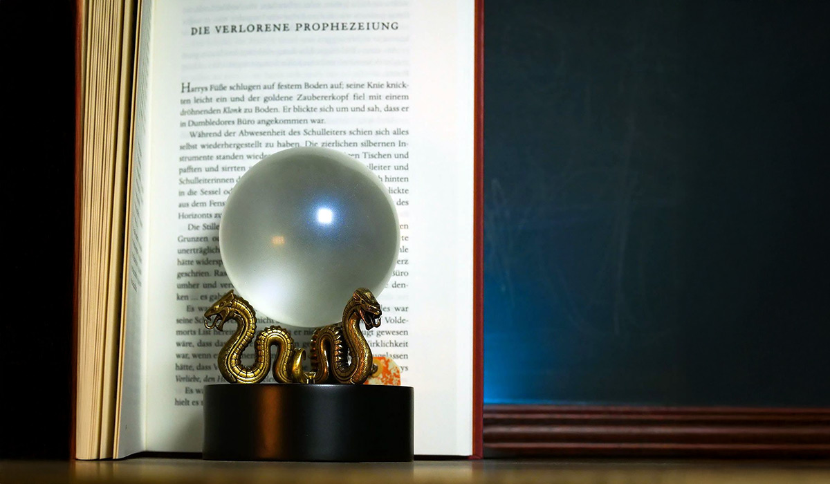 Nachbildung der ersten Prophezeiung von Sybill Trelawney vor dem aufgeschlagenen Buch „Harry Potter und der Orden des Phönix“, Kapitel „Die verlorene Prophezeiung“.