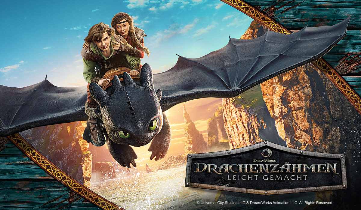 Zwei Jugendliche reiten auf dem Drachen Ohnezahn über eine felsige Küste. Unten das Logo von „Drachenzähmen leicht gemacht“.