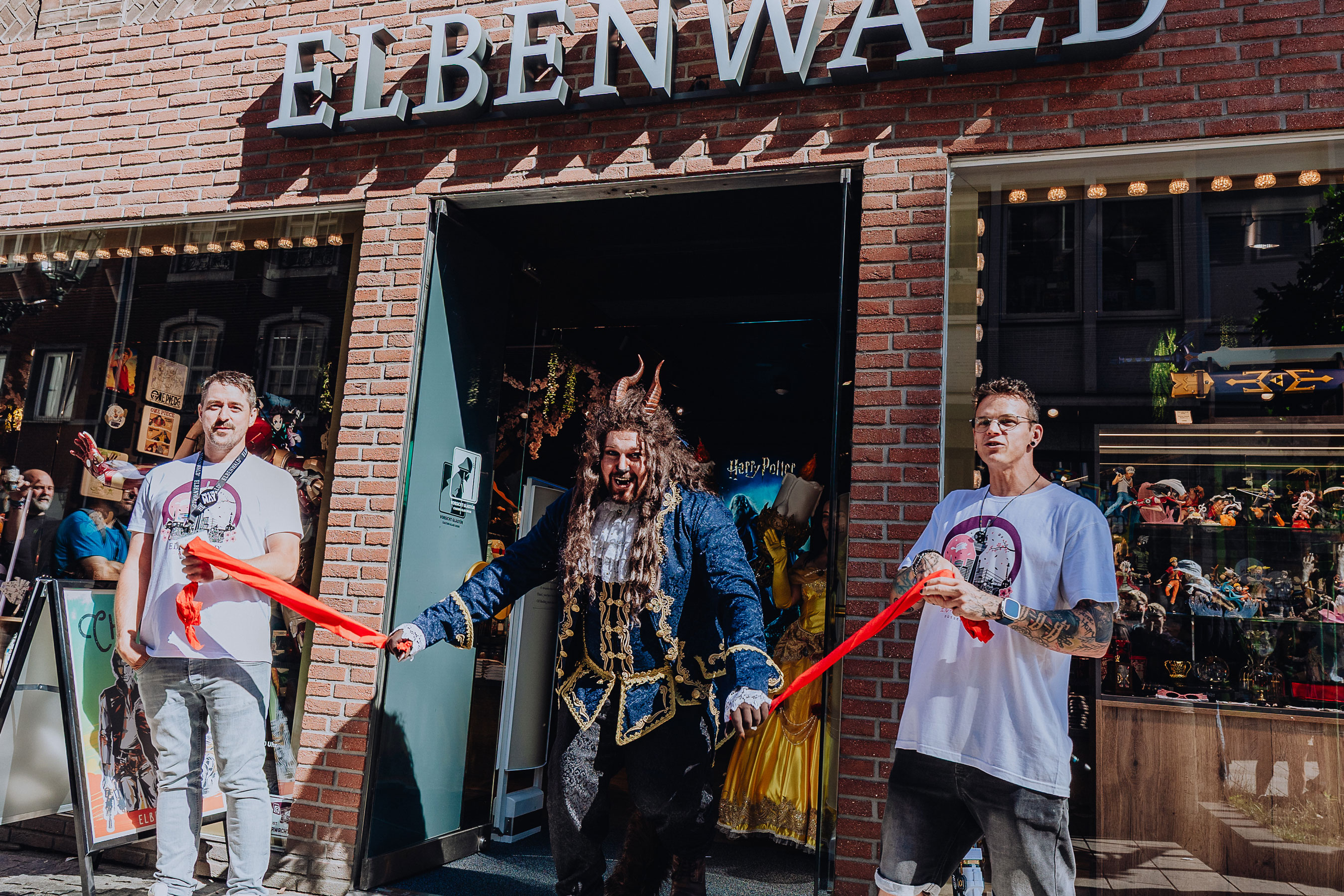 A cosplayer dressed as the Beast from Beauty and the Beast opens the new store in Düsseldorf, flanked by two Elbenwald employees.