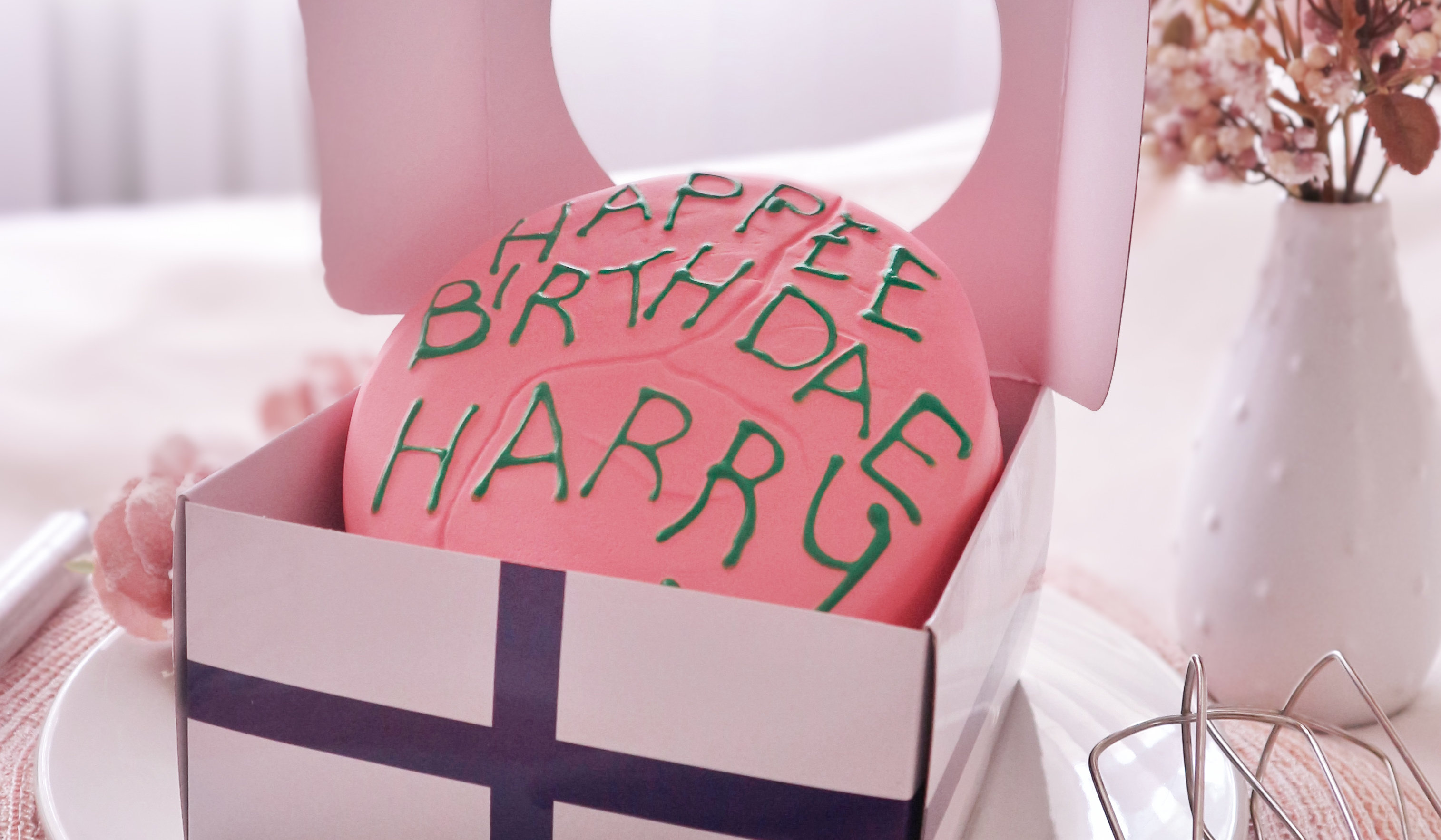 A pink birthday cake with green icing spelling “HAPPEE BIRTHDAE HARRY”. Anti-stress figure inspired by Hagrid’s cake from “Harry Potter and the Philosopher’s Stone”.