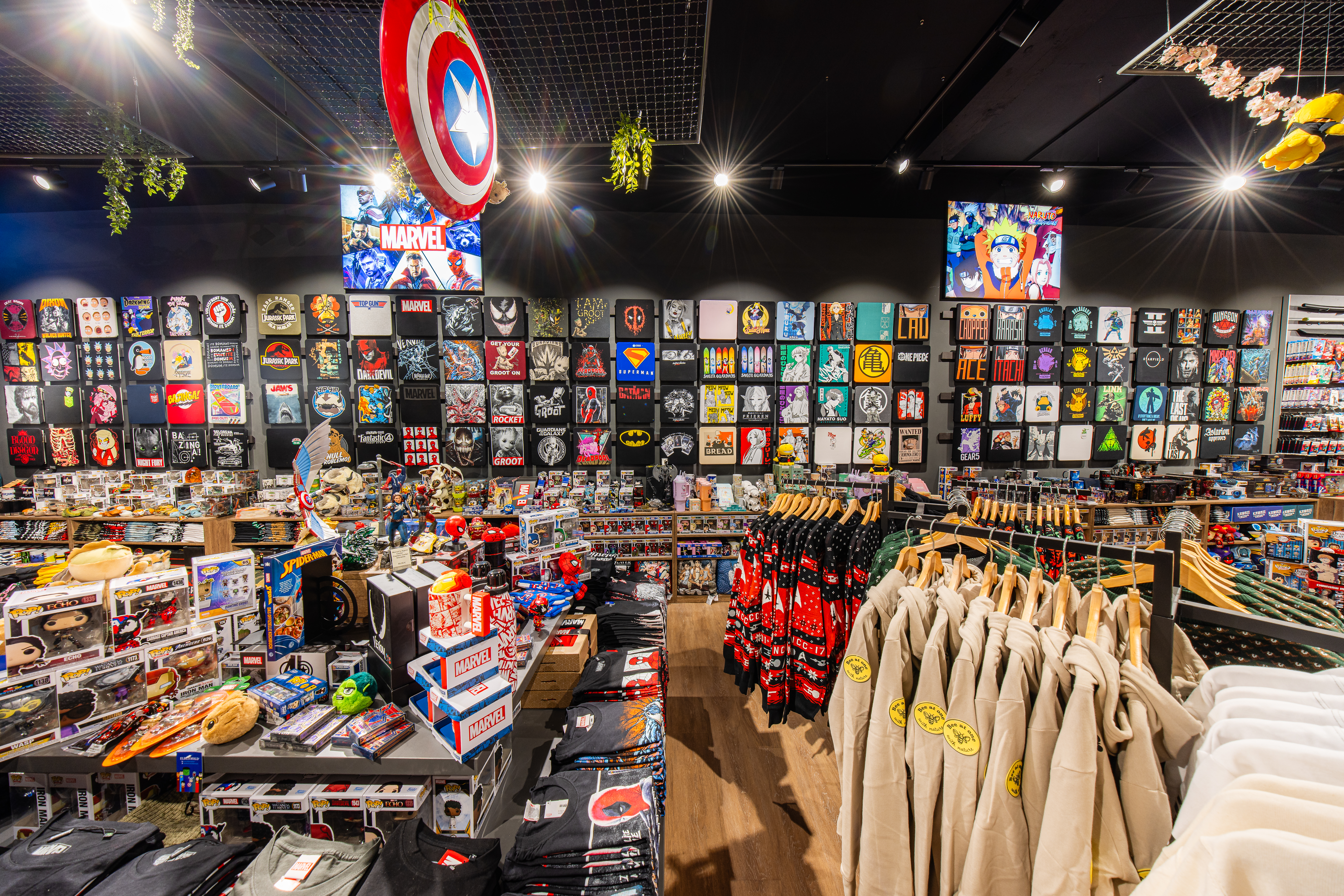 Parete del negozio piena di magliette e articoli di cultura pop e gaming.