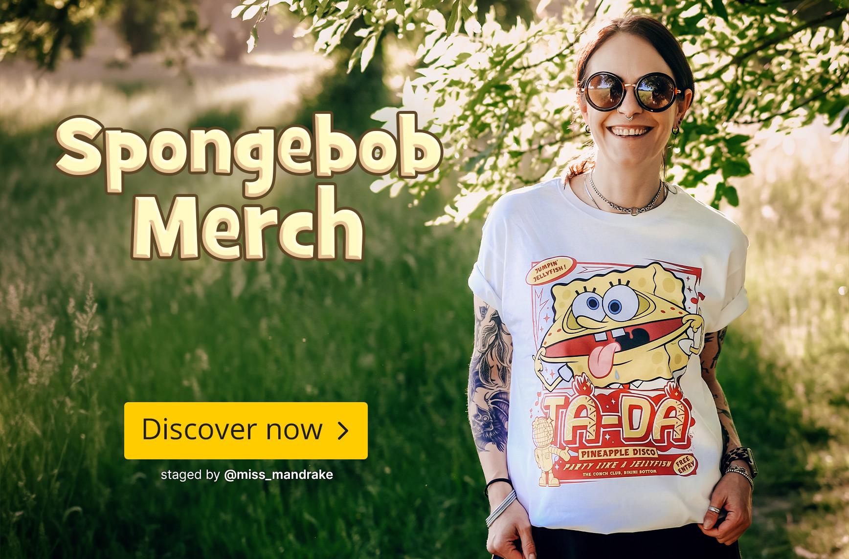 A person wearing sunglasses and showing visible tattoos stands on a sunny woodland path, wearing a white SpongeBob T-shirt with a colourful graphic design. The scene has a cheerful summer atmosphere. Text in the image: “SpongeBob Merchandise” and the butt
