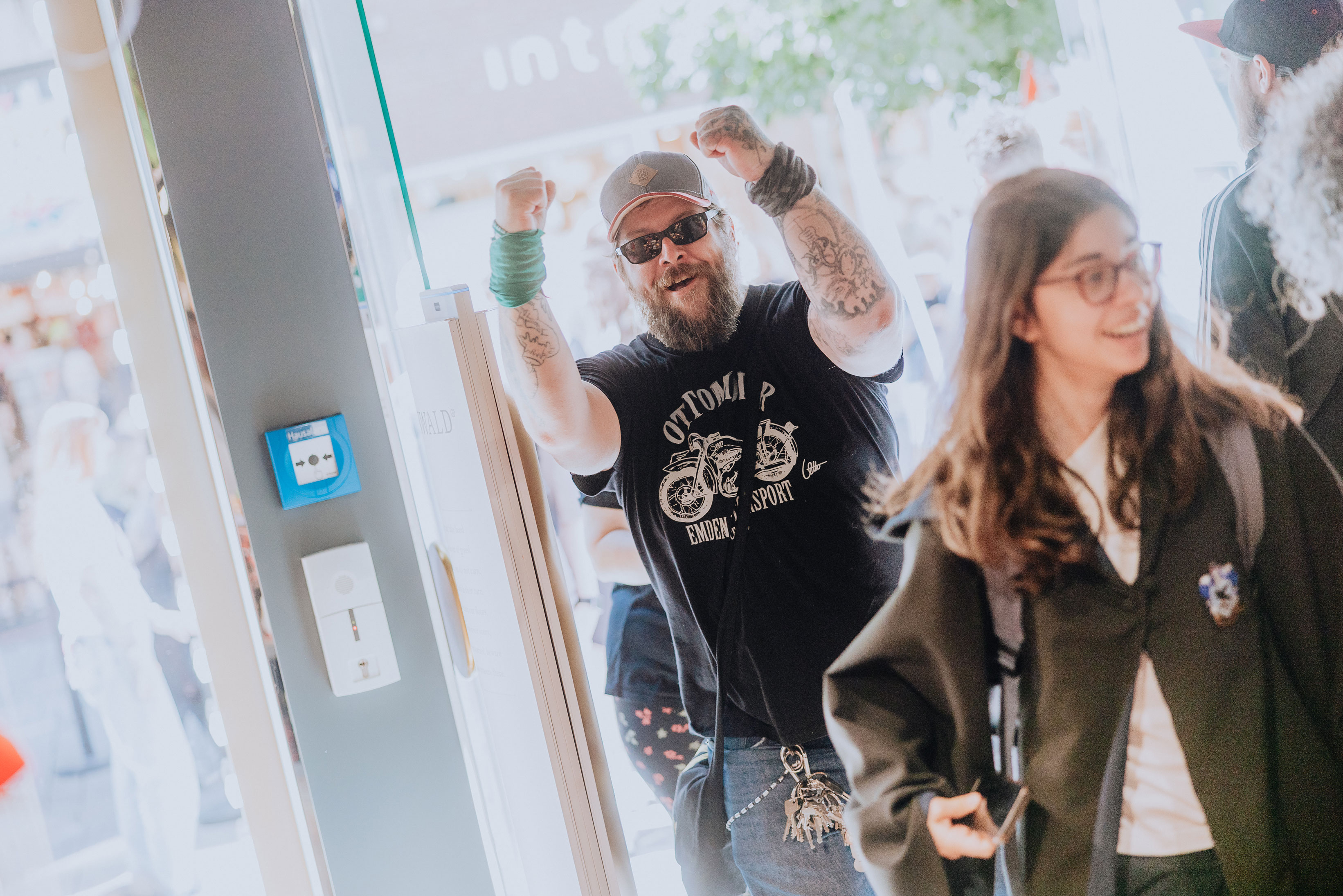 An excited customer with a thick beard and sunglasses enters the Elbenwald store.