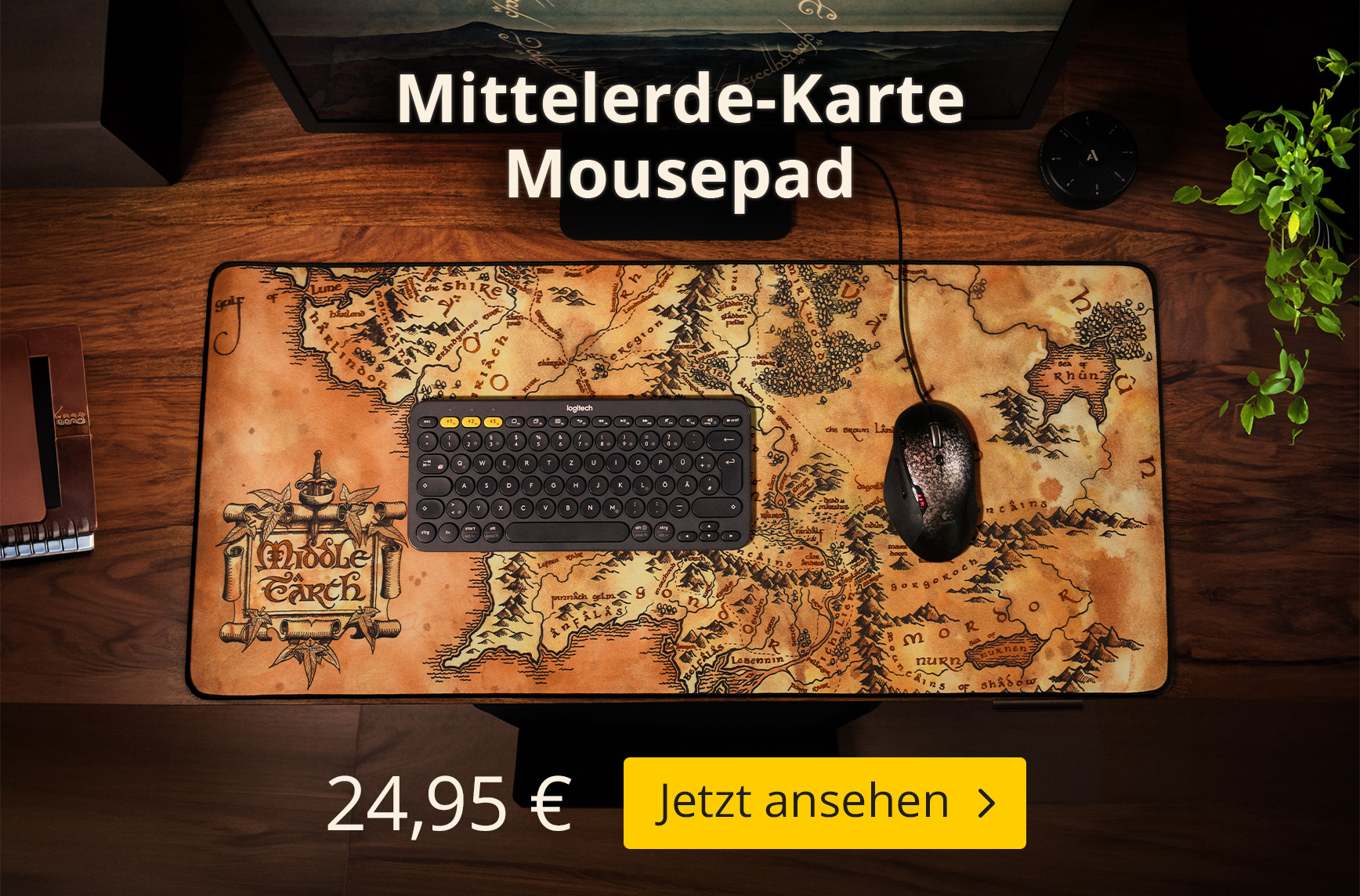 Ein großes Der Herr der Ringe Mousepad mit der Karte von Mittelerde liegt auf einem Holzschreibtisch und dient als Unterlage für Tastatur und Maus. Text im Bild: „Mittelerde-Karte Mousepad“, Preis 24,95 € sowie der Button „Jetzt ansehen“.