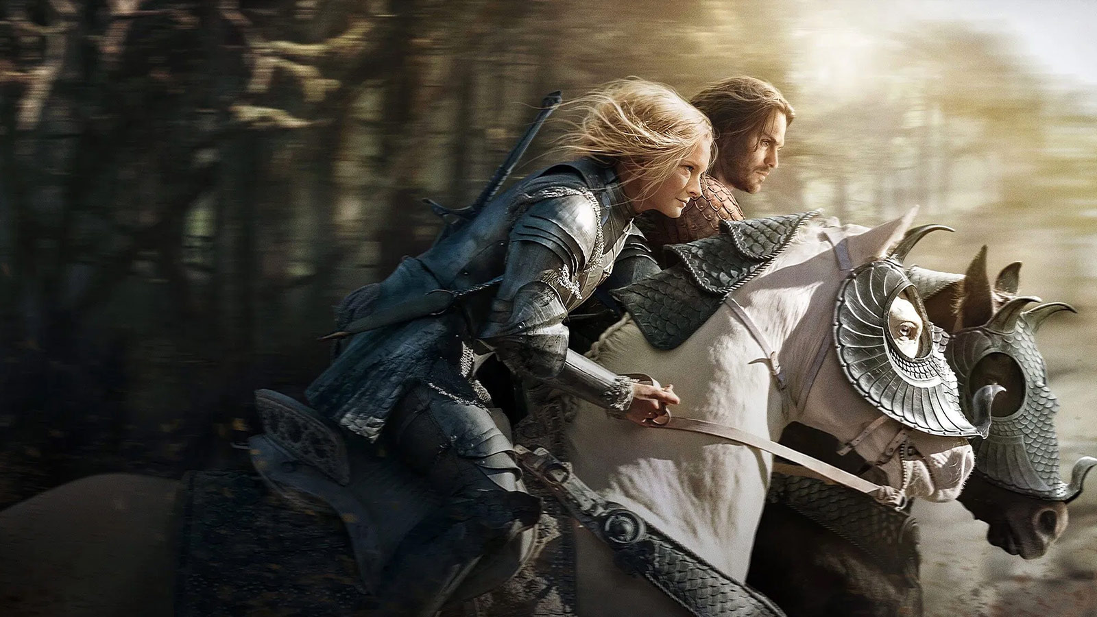 Galadriel reitet in voller Rüstung an der Seite eines Gefährten durch einen dichten Wald. Beide sind auf gepanzerten Pferden unterwegs, mit ernsten Blicken und Zielstrebigkeit. Die Szene stammt aus der Serie „Die Ringe der Macht”.