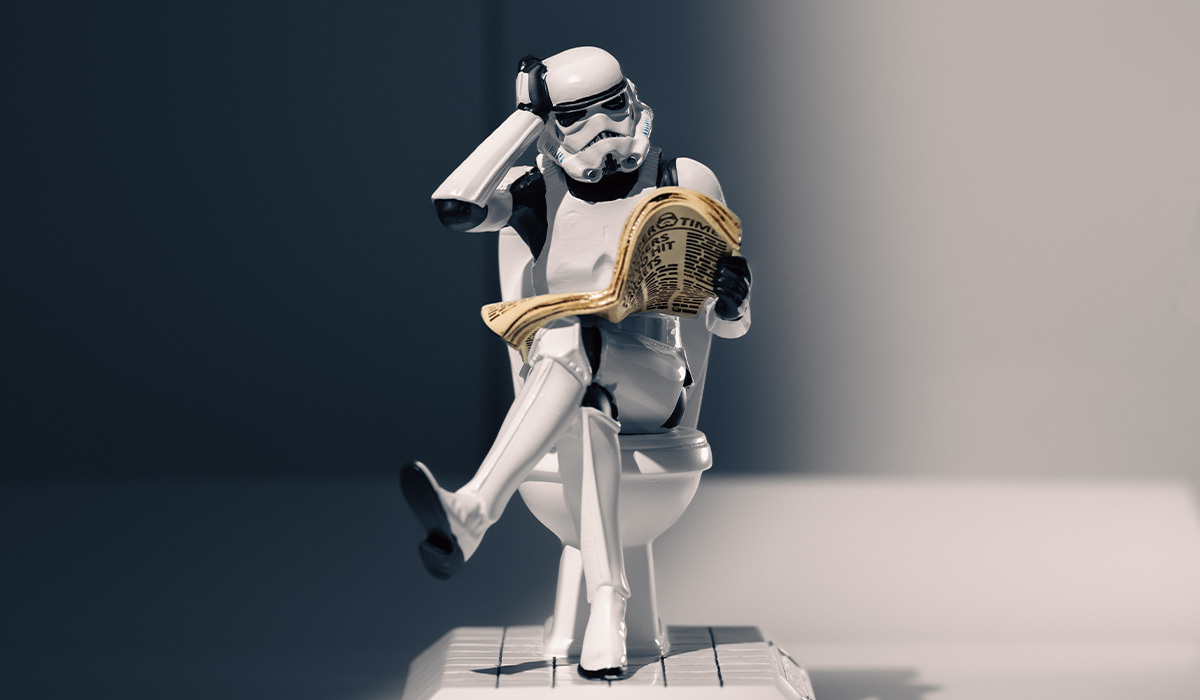 A toy Stormtrooper sits pensively on a toilet while reading a newspaper – a playful and humorous Star Wars-themed scene