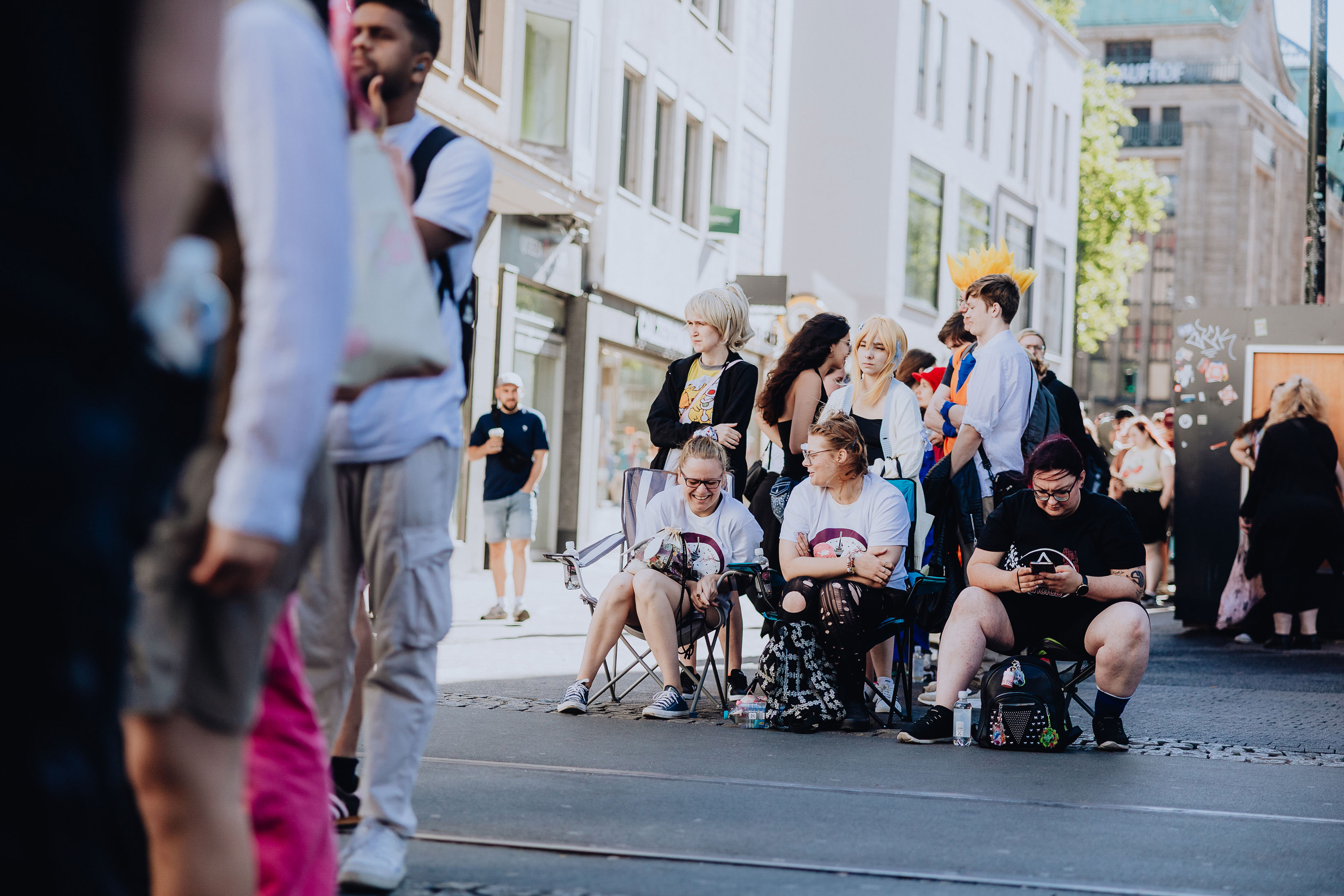 A group of fans, some in costume, sit outside waiting for the new Elbenwald store in Düsseldorf to open.