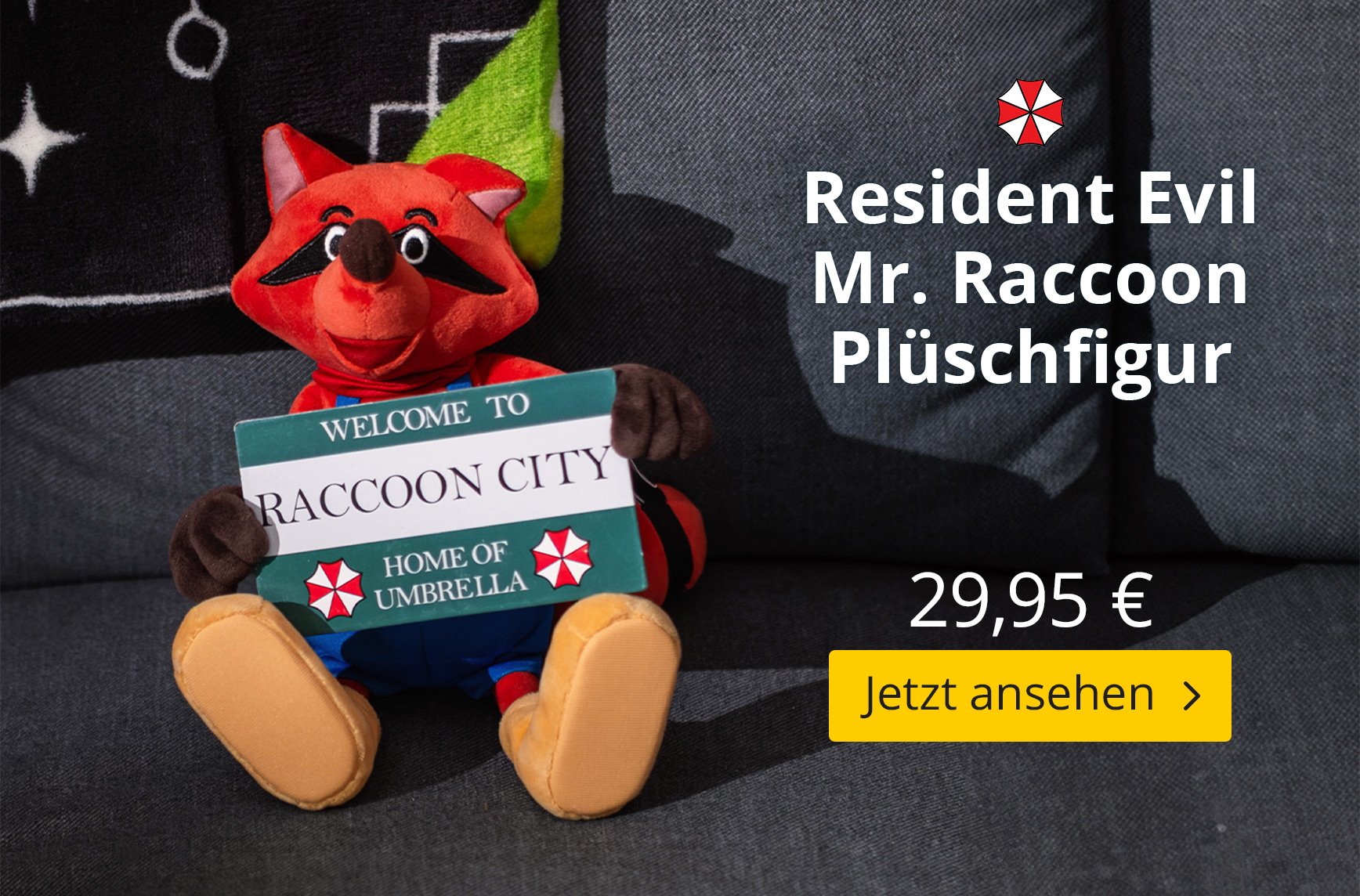 Rote Mr. Raccoon Plüschfigur aus Resident Evil sitzt auf einem dunklen Sofa und hält ein Schild mit der Aufschrift „Welcome to Raccoon City – Home of Umbrella“. Im Bild stehen außerdem „Resident Evil Mr. Raccoon Plüschfigur“, der Preis 29,95 € sowie der B