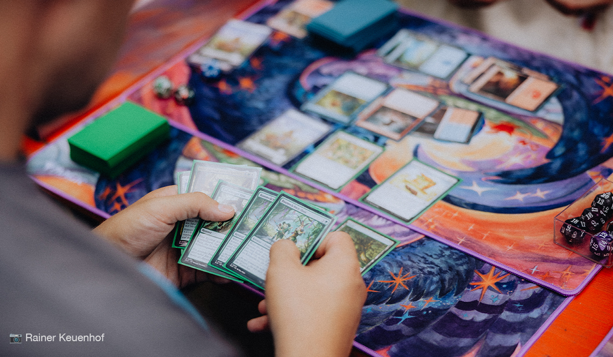 Das Titelbild zeigt ein laufendes Magic the Gathering Duell zwischen zwei Spielern.